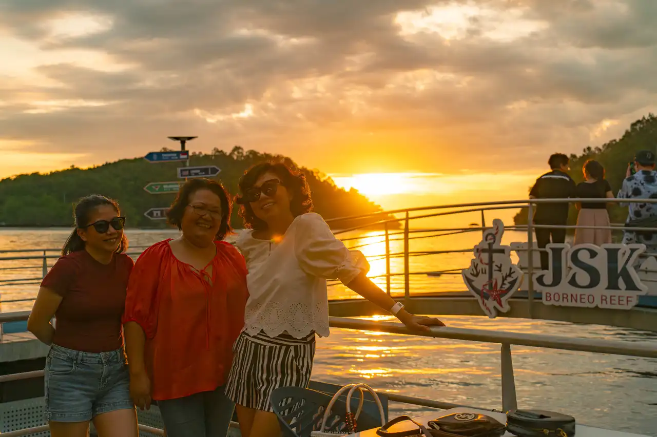 Three women smiling during a sunset at JSK Borneo Reef.