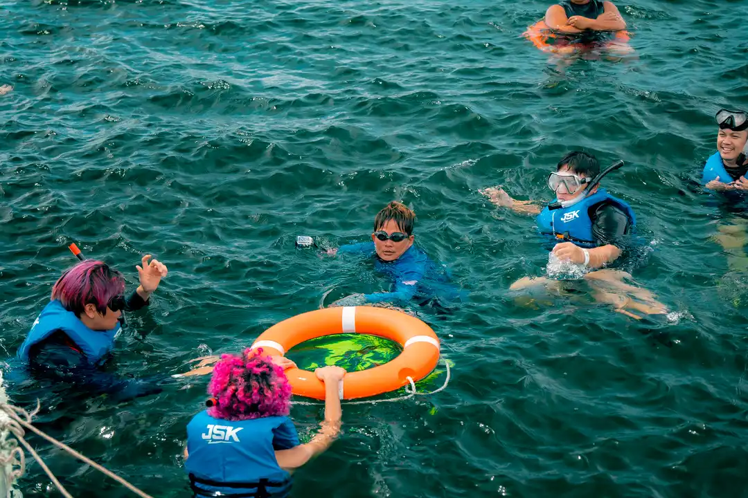 Group of people enjoying a snorkeling tour in Kota Kinabalu, Sabah, with life jackets and snorkeling gear.
