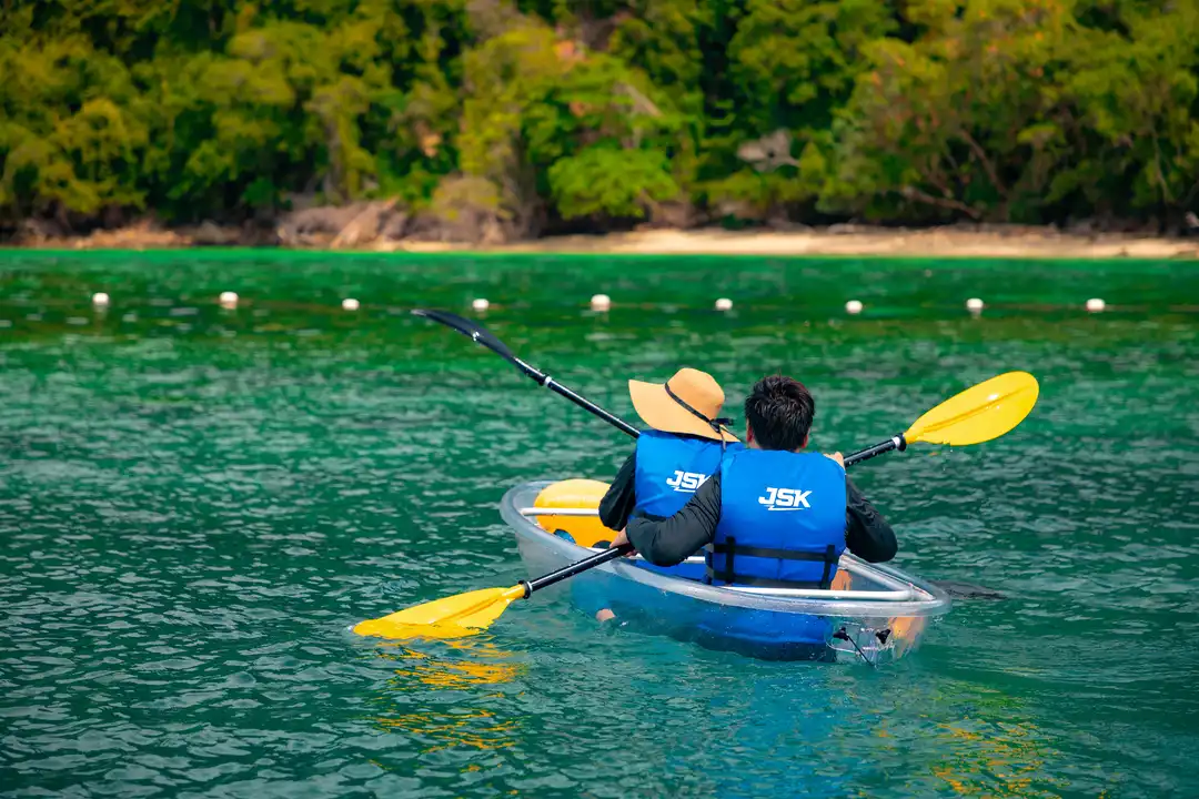 Two people kayaking in clear waters near Kota Kinabalu, Sabah, wearing JSK life jackets.